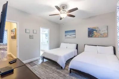two beds in a room with a desk and a ceiling fan at 3BR Townhouse w Perfect Location in Orlando