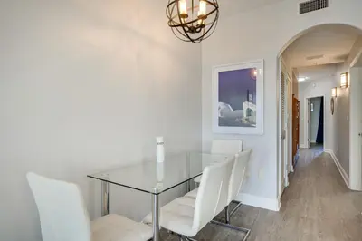 a dining room with a glass table and white chairs at 1 Mi to Disney World Lakefront Condo in Orlando! in Orlando