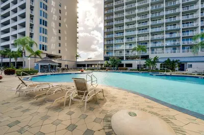 a swimming pool with chairs and a large building at 1 Mi to Disney World Lakefront Condo in Orlando! in Orlando