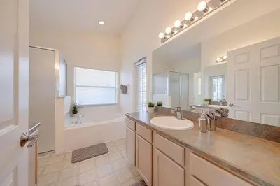 a bathroom with a sink and a tub and a mirror at 545 -Beautiful 4 Bed Home with Sparkling Pool and Games Room in Orlando