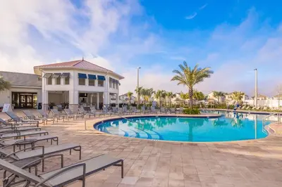 a swimming pool with chairs and a building at Luxury Villa inside Storey Lake, Kissimmee - No Extra Fees in Kissimmee