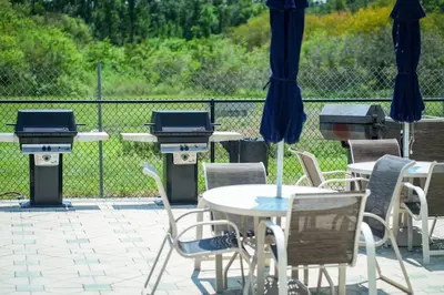 a patio with tables and chairs and a grill at Aparment 2nd floor 5 minutes from Disney in Orlando