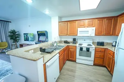 a kitchen with wooden cabinets and a white stove top oven at Aparment 2nd floor 5 minutes from Disney in Orlando