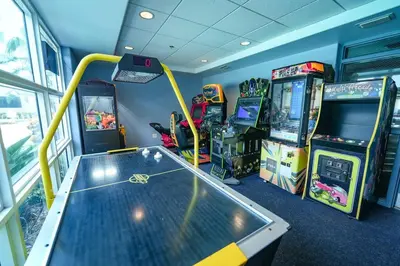 a gaming room with arcade games and a table at Orlando Apt 9th Floor 5 min from Disney in Orlando
