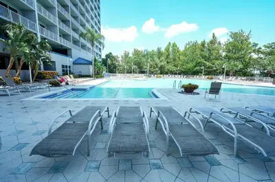 a swimming pool with tables and chairs next to a building at Orlando Apt 10th floor 5 min from Disney in Orlando