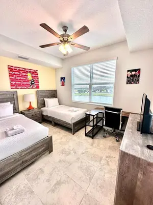 a bedroom with two beds and a ceiling fan at The Epic Miami Supreme Storey Lake in Kissimmee