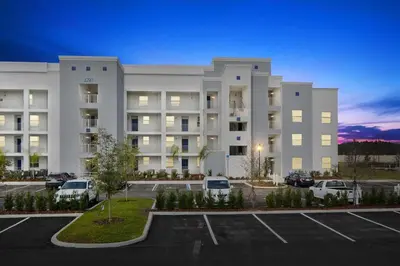 a large white building with cars parked in a parking lot at The Epic Miami Supreme Storey Lake in Kissimmee
