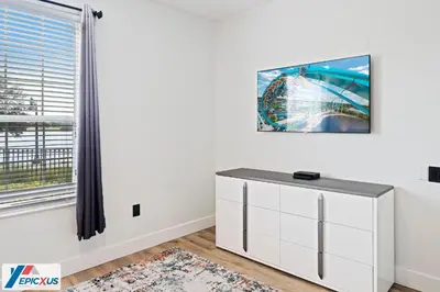 a white living room with a tv on the wall at The Epic Madrid Vista Cay Orlando in Orlando