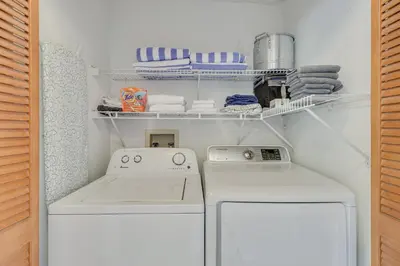 a small laundry room with two washes and towels at 6 Mi to Disney Family-Friendly Condo in Kissimmee in Kissimmee