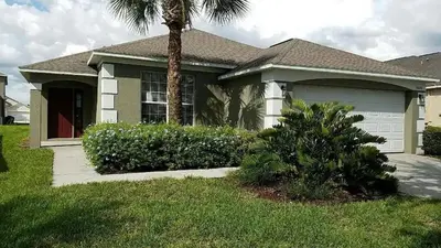a house with a palm tree in front of it at 4 BED 3 BATH IN A GATED COMMUNITY WITH POOL villa in Kissimmee