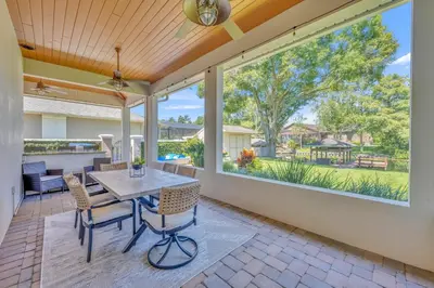 a patio with a table and chairs and a large window at Best of Both Worlds Lakehouse in Orlando
