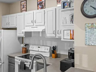 a kitchen with white cabinets and a clock on the wall at Theme Park Paradise! in Kissimmee