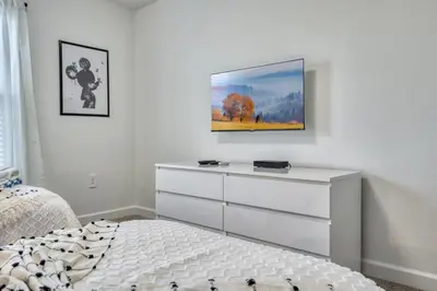 a bedroom with a white dresser and a tv on the wall at Ultimate Luxury Home-Private Pool Themed Bedroom in Kissimmee