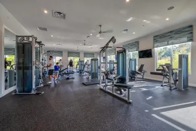 a gym with cardio equipment and people in the background at Ultimate Luxury Home-Private Pool Themed Bedroom in Kissimmee