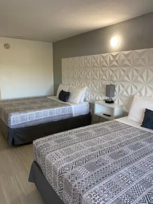 a hotel room with two beds and a lamp at A & S Vacation Rooms in Kissimmee