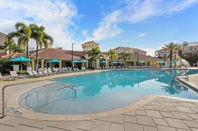 a large swimming pool with chairs and palm trees at Orlando Resort: 3BD and electric fireplace in Orlando