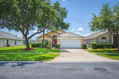 a family house with a driveway and trees at Charming 3BR home in Kissimmee with private pool and lake view, perfect for families. in Kissimmee
