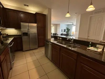 a kitchen with wooden cabinets and a stainless steel refrigerator at Vista Cay Jewel Luxury By Universal Orlando Rental in Orlando