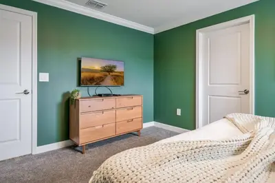 a bedroom with green walls and a bed and a dresser at Opulent Retreat Themed Bedrooms and Pool Paradise in Kissimmee