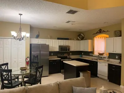 a kitchen with a table and a kitchen with white cabinets at Complete Vacation in exclusive 7 Bed resort home, in Kissimmee