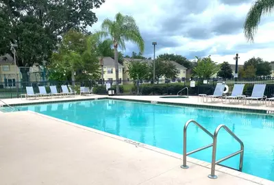 a swimming pool with blue water and lounge chairs at Family Friendly Community in Kissimmee