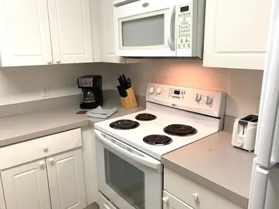 a white kitchen with a stove and a microwave at Family Friendly Community in Kissimmee