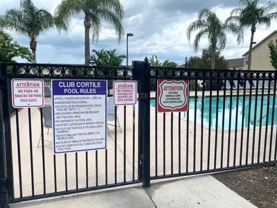 a black fence with signs on it with a swimming pool at Family Friendly Community in Kissimmee