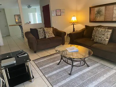 a living room with two couches and a glass table at Family Friendly Community in Kissimmee