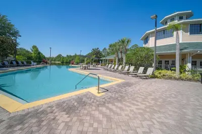 a swimming pool with chairs and a building at Caribe Cove Resort 3BR Condo Apt Disney Orlando in Kissimmee