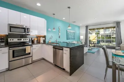 a kitchen with white cabinets and a blue wall at Charming Villa with Private Pool Bliss in Orlando