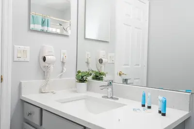a white bathroom with a sink and a mirror at Magical 5-Bedroom Retreat w/ Pool, 3 Ensuite Bedrooms, Near Disney, and Internet! in Kissimmee