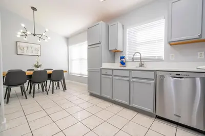 a kitchen with white cabinets and a table with chairs at Magical 5-Bedroom Retreat w/ Pool, 3 Ensuite Bedrooms, Near Disney, and Internet! in Kissimmee