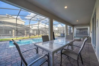 a patio with a table and chairs and a pool at Family Paradise Space Themed Perfect Location in Kissimmee