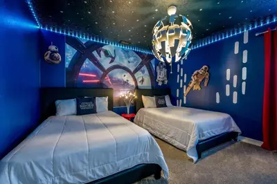 a blue bedroom with two beds and a chandelier at Family Paradise Space Themed Perfect Location in Kissimmee