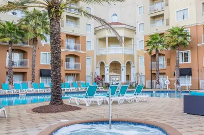 a pool with chairs and palm trees in front of a building at Universal and Convention Center Best Resort Studio in Orlando