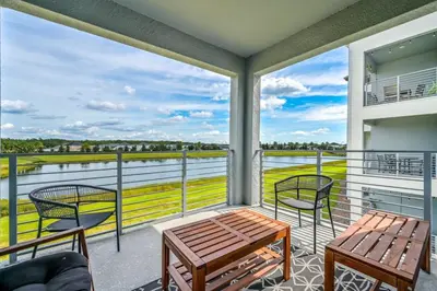 a balcony with a table and chairs and a view of the water at Spacious Beautiful 3-BR Condo Prime Location in Kissimmee