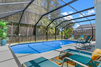 a swimming pool with a glass greenhouse on a house at Beautiful Tropical Home with Private Heated and Chilled Pool in Kissimmee