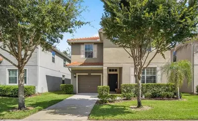 a house with two trees in front of it at 8931 Cuban Palm in Kissimmee