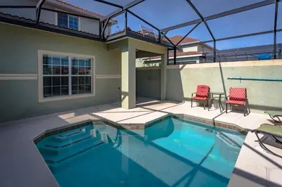 a swimming pool with two red chairs next to a house at 3071 Beach Palm in Kissimmee