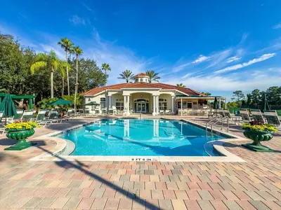 a swimming pool with chairs and a house at 8538 Crystal Cove in Kissimmee