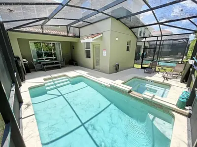 a large swimming pool in a backyard with a house at Banana Palm Paradise home in Kissimmee