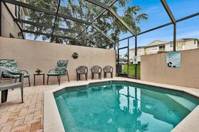 a swimming pool with two chairs and a table and a tablektop at 2319 Silver Palm in Kissimmee