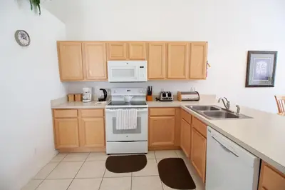 a kitchen with wooden cabinets and a white stove top oven at Private Pool Home at Seasons Community in Kissimmee