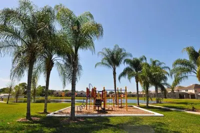 a playground in a park with palm trees at Private Pool Home at Seasons Community in Kissimmee