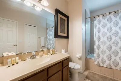 a bathroom with a sink and a toilet and a mirror at Enchanted Villa Oasis in Orlando