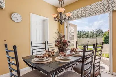 a dining room with a table with chairs and a clock at Enchanted Villa Oasis in Orlando