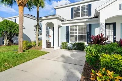 a white house with a palm tree and a sidewalk at 2563 Maneshaw in Orlando