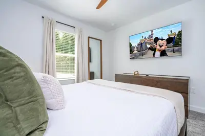 a bedroom with a white bed with a tv on the wall at Wonderfull home near Disney & FREE Waterpark 2421 in Kissimmee