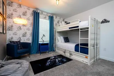 a bedroom with two bunk beds and a chair at Luxury 5BR Storey Lake Retreat Near Disney 2969 in Kissimmee