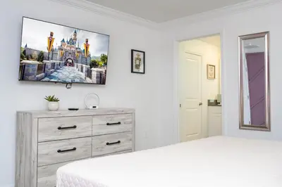 a bedroom with a dresser and a tv on the wall at Lake view & Free Resort Access near Disney 4399 in Kissimmee